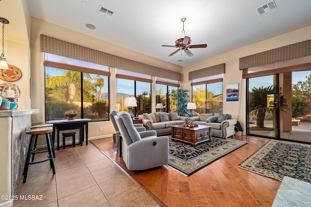 living area with wood finished floors, visible vents, and a ceiling fan