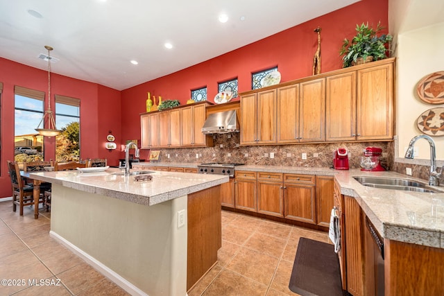 kitchen featuring wall chimney range hood, a sink, visible vents, and decorative backsplash