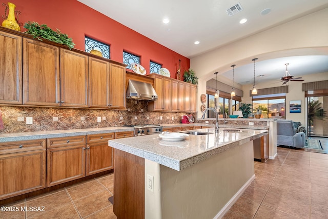 kitchen featuring visible vents, stove, light tile patterned flooring, a sink, and wall chimney exhaust hood