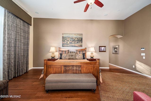 bedroom featuring arched walkways, wood finished floors, and baseboards