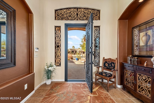 foyer featuring baseboards and arched walkways