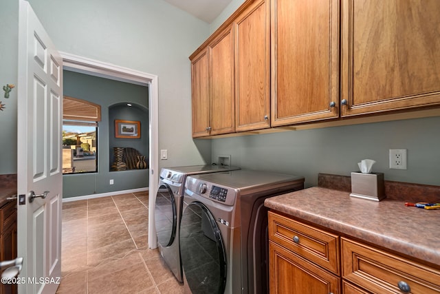 washroom with light tile patterned floors, separate washer and dryer, cabinet space, and baseboards