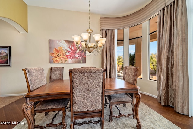 dining space with an inviting chandelier, wood finished floors, and baseboards