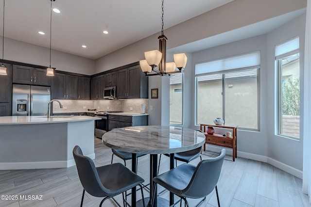 kitchen featuring sink, appliances with stainless steel finishes, dark brown cabinetry, decorative backsplash, and decorative light fixtures