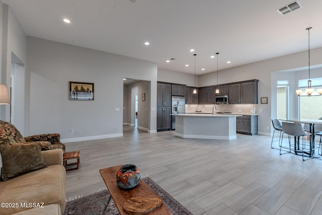 living room with sink, a chandelier, and light wood-type flooring