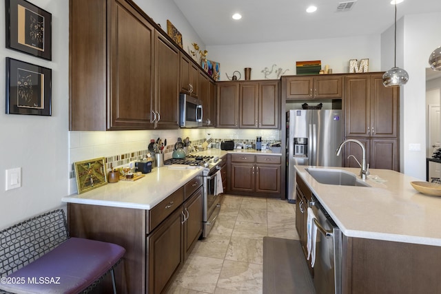 kitchen with appliances with stainless steel finishes, pendant lighting, tasteful backsplash, sink, and dark brown cabinetry