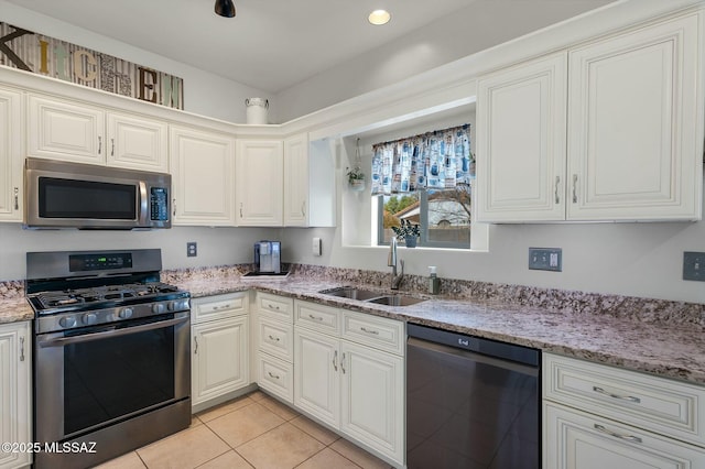 kitchen with sink, white cabinetry, light tile patterned floors, stainless steel appliances, and light stone countertops