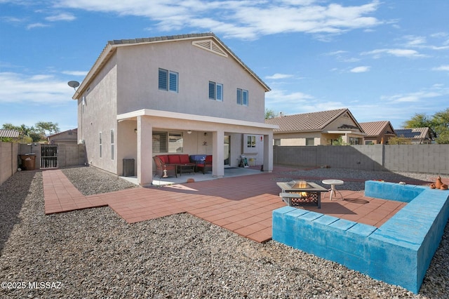 rear view of house with an outdoor living space with a fire pit and a patio