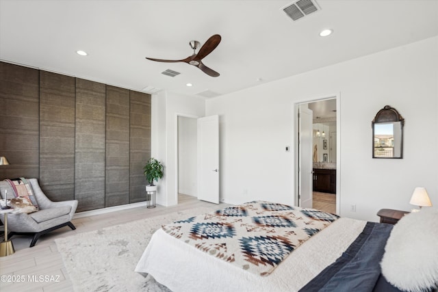 bedroom featuring ceiling fan, ensuite bath, and light hardwood / wood-style flooring