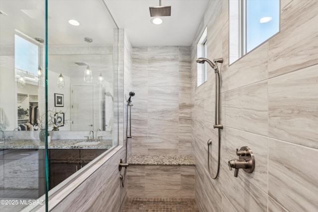 bathroom with a tile shower and sink