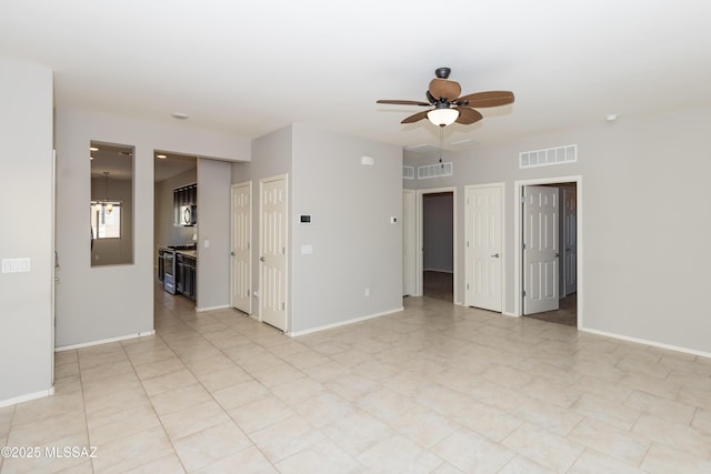 tiled spare room with ceiling fan with notable chandelier