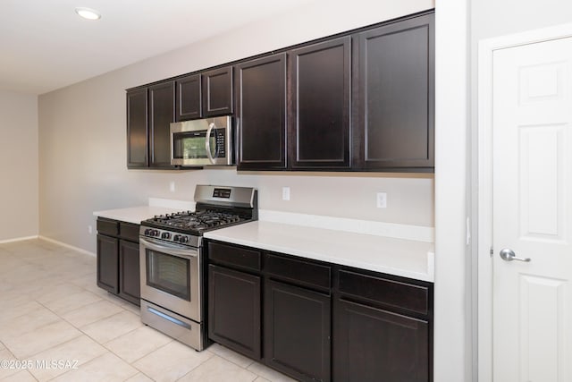 kitchen featuring stainless steel appliances, light tile patterned floors, and dark brown cabinetry