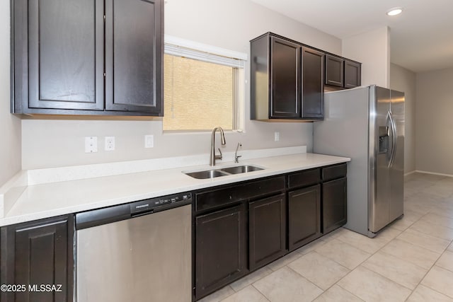 kitchen with appliances with stainless steel finishes, sink, light tile patterned floors, and dark brown cabinetry