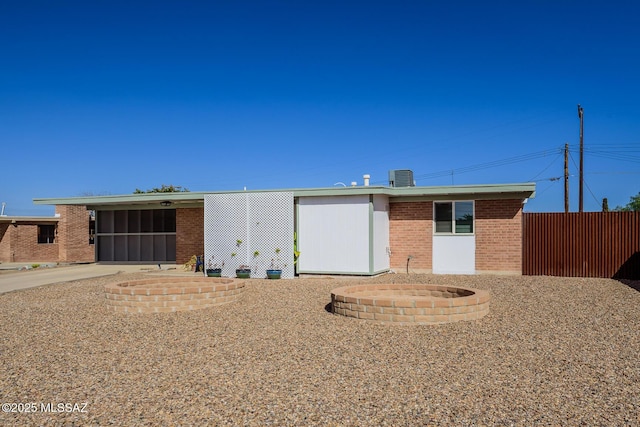 ranch-style house with fence, central AC, and brick siding