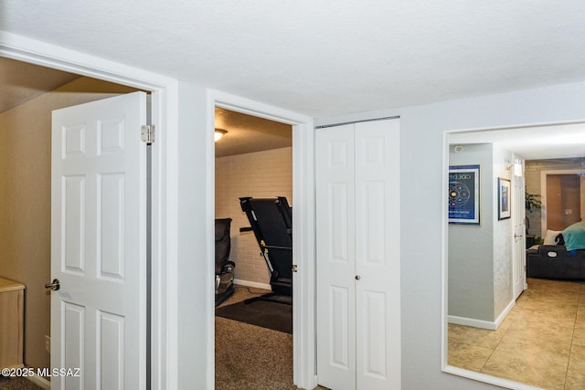 hall with tile patterned flooring, a textured ceiling, and baseboards