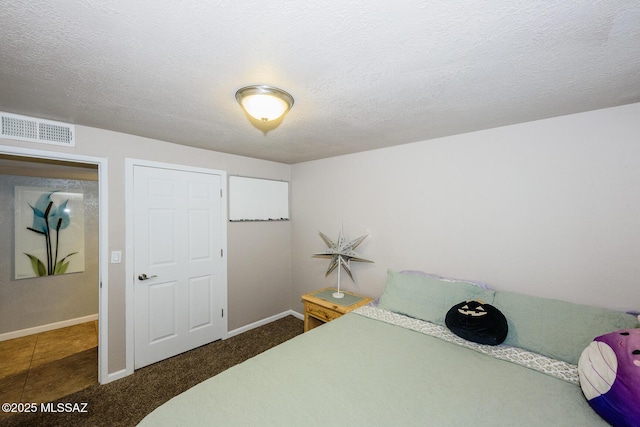 bedroom featuring visible vents, a textured ceiling, and baseboards