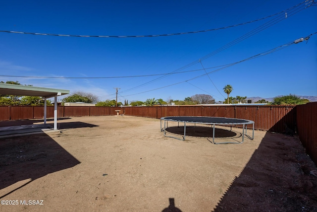 view of yard with a trampoline and a fenced backyard