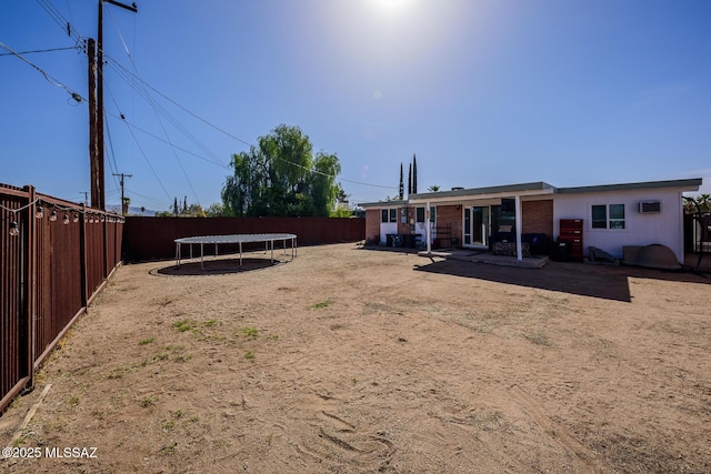 view of yard featuring a trampoline, a fenced backyard, and a patio