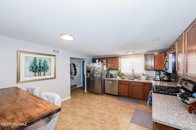 kitchen featuring stainless steel appliances, brown cabinetry, light countertops, and a sink