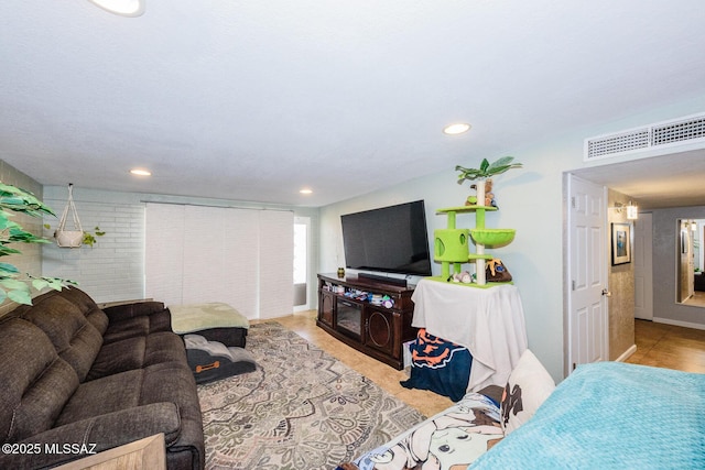 living room with recessed lighting, visible vents, and brick wall