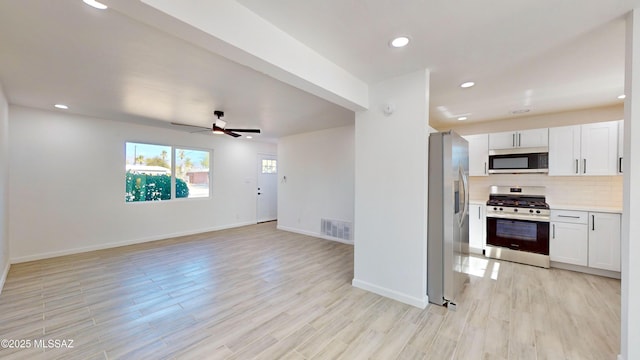 kitchen featuring white cabinetry, appliances with stainless steel finishes, light hardwood / wood-style floors, and decorative backsplash