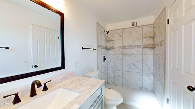 bathroom with vanity, toilet, and tiled shower