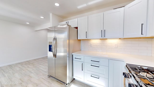 kitchen featuring stainless steel appliances, white cabinetry, light hardwood / wood-style flooring, and decorative backsplash