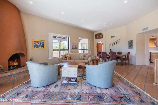 living area with arched walkways, a fireplace, visible vents, and tile patterned floors