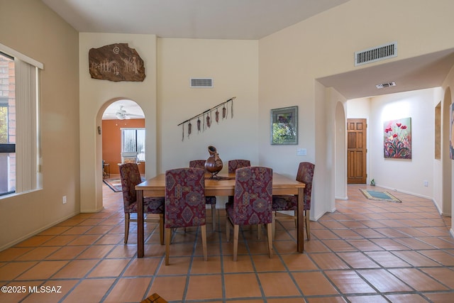 dining room featuring arched walkways, light tile patterned floors, and visible vents