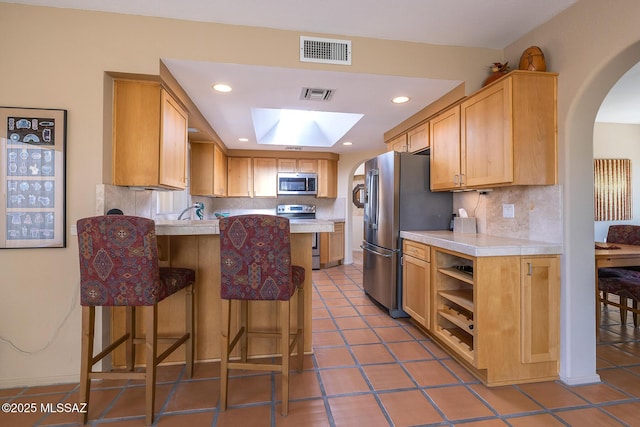 kitchen featuring a peninsula, visible vents, stainless steel appliances, and light countertops