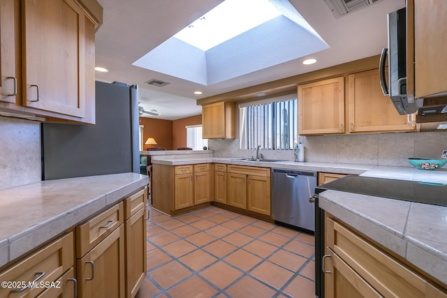 kitchen with a peninsula, a sink, visible vents, appliances with stainless steel finishes, and tasteful backsplash