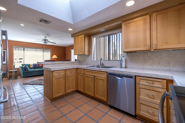 kitchen featuring a peninsula, a sink, visible vents, open floor plan, and dishwasher