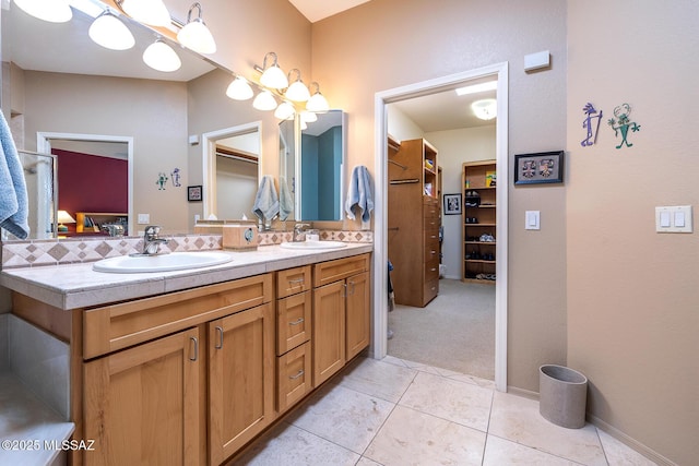 bathroom featuring double vanity, a walk in closet, and a sink