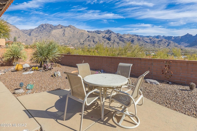 view of patio with outdoor dining space, a fenced backyard, and a mountain view