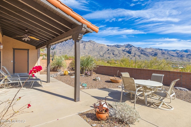 view of patio featuring a fenced backyard, a mountain view, outdoor dining area, and a ceiling fan