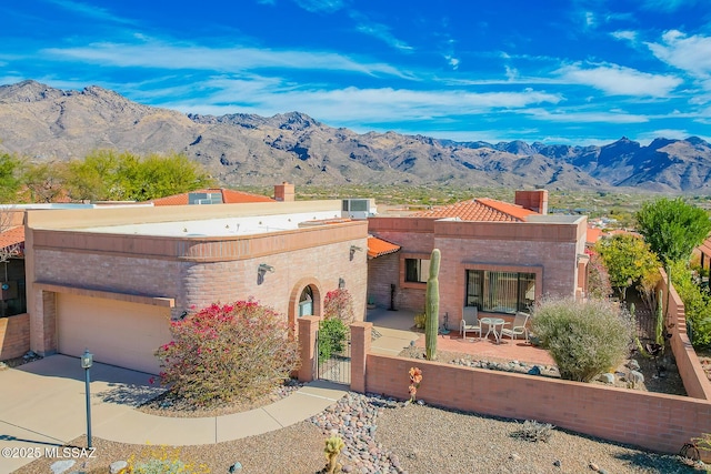 view of front of house with a mountain view, a garage, driveway, a gate, and a patio area