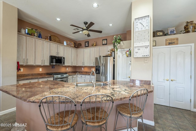 kitchen with stainless steel appliances, a kitchen bar, stone countertops, and sink