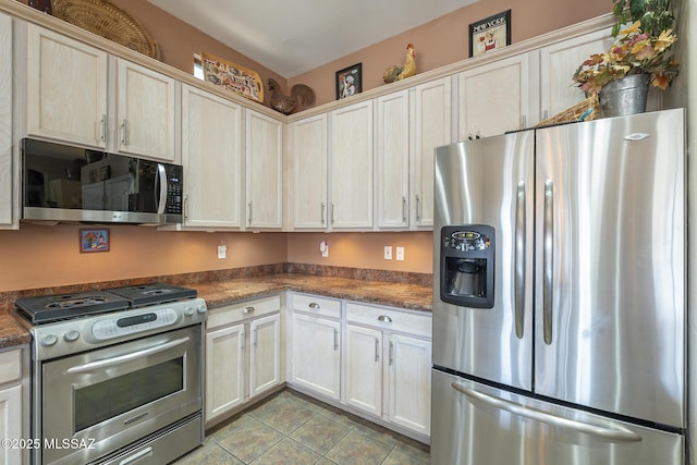 kitchen featuring dark stone countertops, appliances with stainless steel finishes, and light tile patterned floors