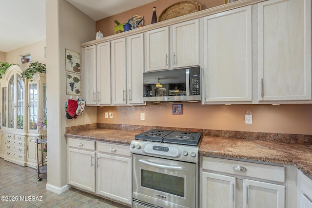 kitchen with appliances with stainless steel finishes, light tile patterned floors, and dark stone counters