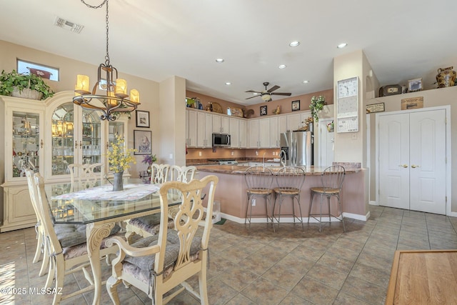 tiled dining space with ceiling fan with notable chandelier