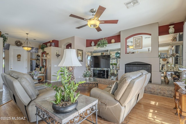 living room with ceiling fan, light hardwood / wood-style floors, and a tile fireplace