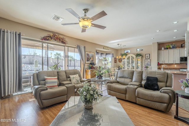 living room with sink, ceiling fan, and light hardwood / wood-style flooring