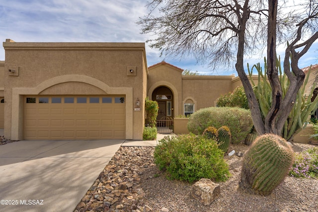 view of front of house with stucco siding, a garage, driveway, and a gate