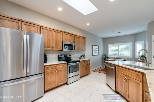 kitchen featuring brown cabinets, a sink, appliances with stainless steel finishes, a skylight, and hanging light fixtures