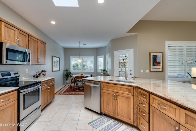 kitchen with brown cabinets, a sink, stainless steel appliances, light tile patterned flooring, and hanging light fixtures