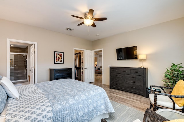 bedroom with wood finished floors, visible vents, ceiling fan, a closet, and a walk in closet