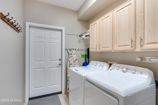 washroom with washing machine and dryer, light tile patterned floors, and cabinet space