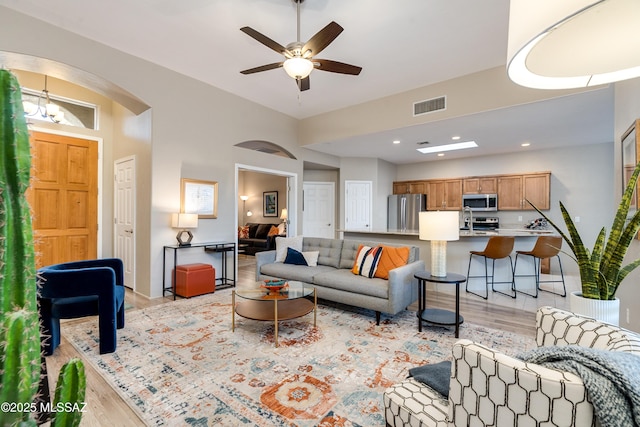 living area with visible vents, light wood finished floors, and ceiling fan