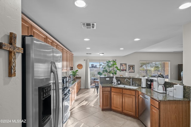 kitchen with sink, light tile patterned floors, stainless steel appliances, and dark stone counters