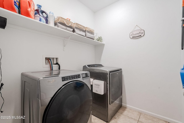 laundry area featuring washing machine and clothes dryer and light tile patterned floors